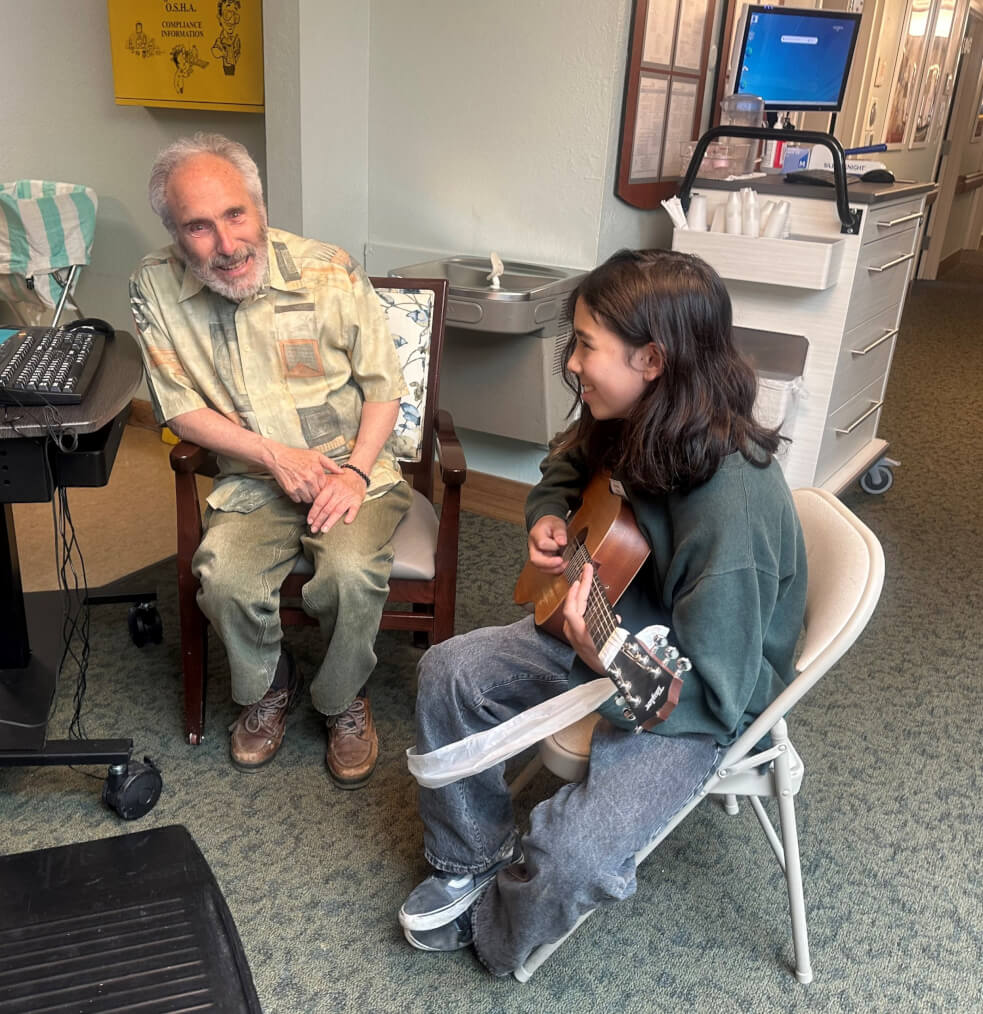 student volunteering with senior for guitar lesson